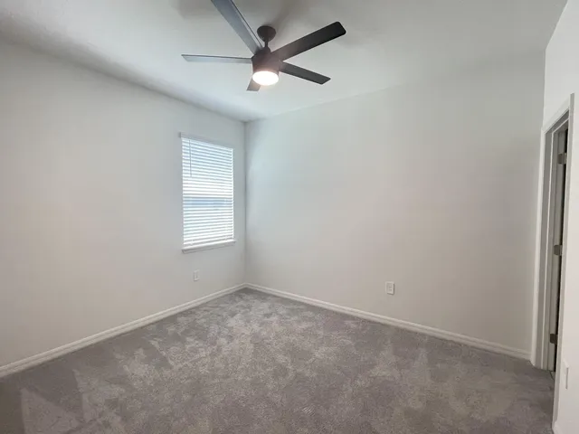 an empty room with a window and a fan
