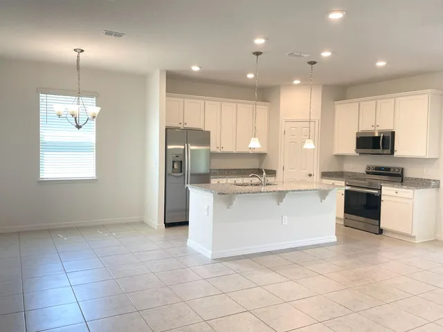 a large kitchen with stainless steel appliances granite countertop a stove a sink and a refrigerator