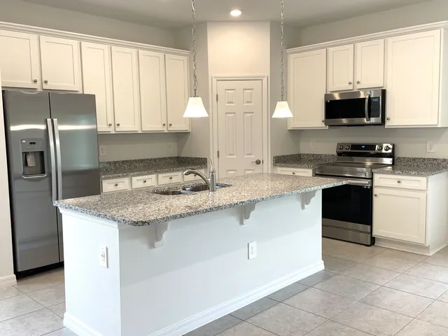 a kitchen with stainless steel appliances granite countertop a sink a stove a microwave and a refrigerator