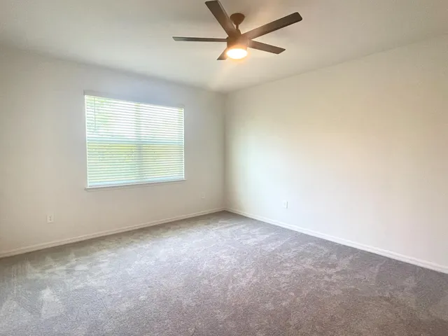 an empty room with a window and a ceiling fan