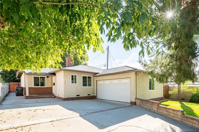 a front view of a house with a garden and trees