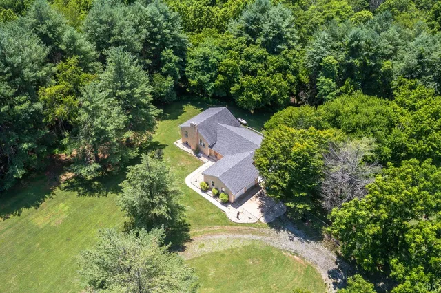 an aerial view of residential house with outdoor space and trees all around