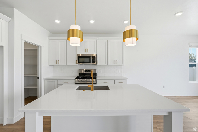 401 West 3085 South, Unit 329 Nibley, UT 84321 - Photo 15 of 34 Kitchen featuring white cabinets, stainless steel appliances, light wood finished floors, light stone counters, and decorative backsplash