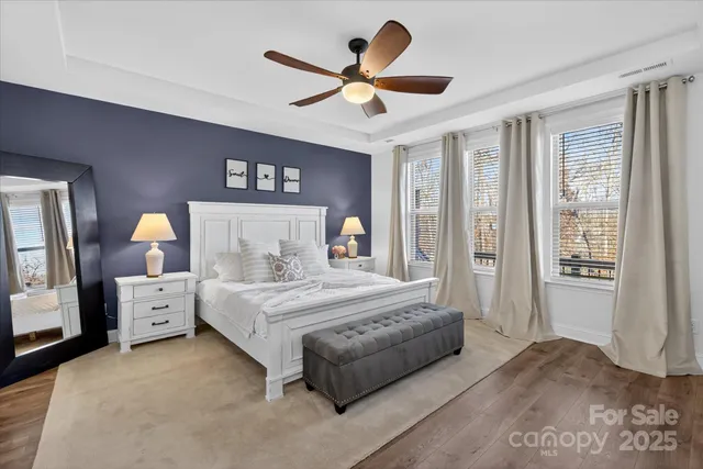 a bedroom with a large bed and a chandelier fan