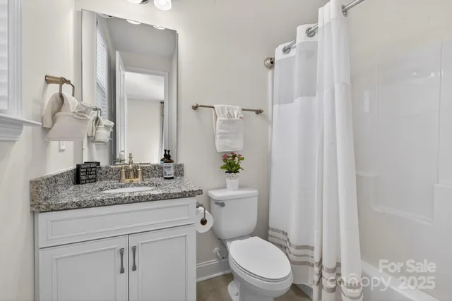 a bathroom with a granite countertop sink mirror vanity and toilet