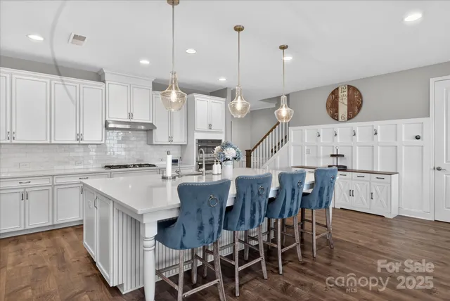 a kitchen with a table chairs a sink dishwasher a dining table and chairs with wooden floor