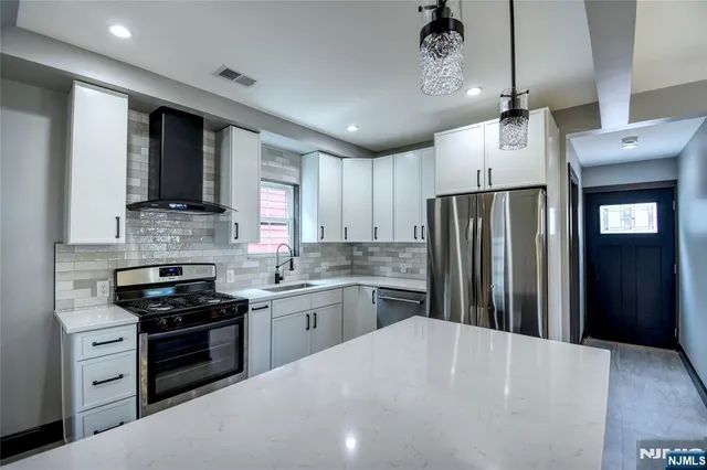 a kitchen with refrigerator a stove and a sink with cabinets