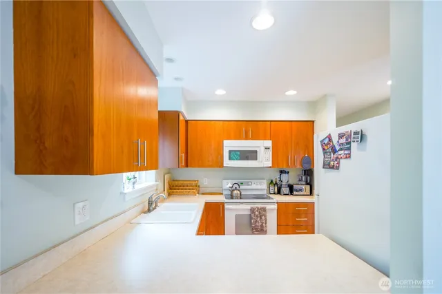 a kitchen with stainless steel appliances a white stove top oven a sink and a refrigerator