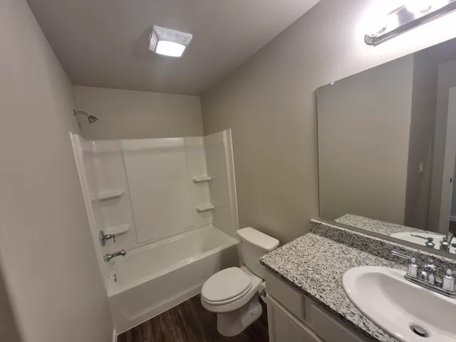 a bathroom with a granite countertop sink toilet mirror vanity and shower