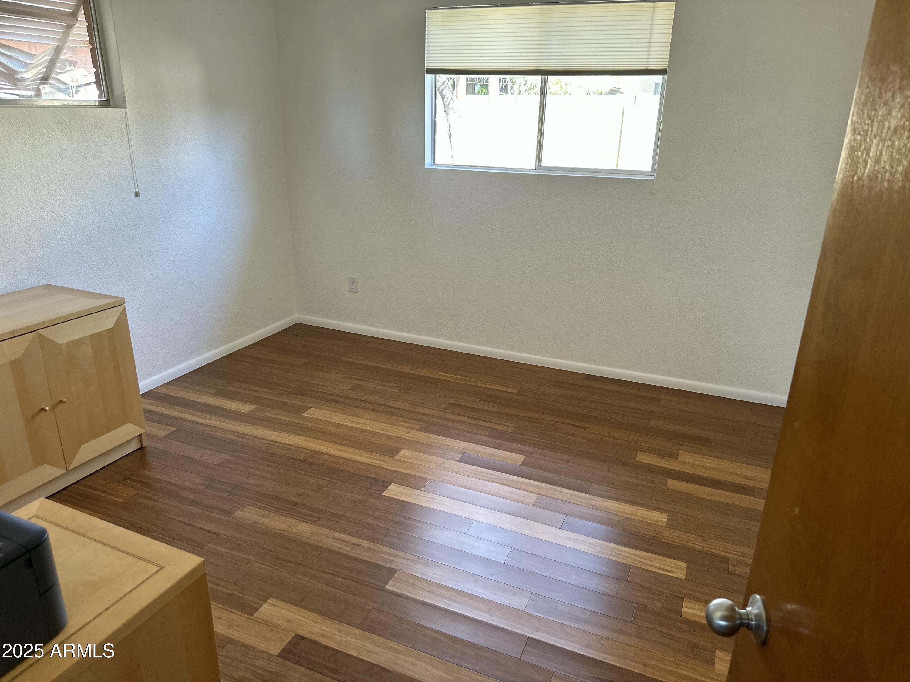 2752 West Lawrence Road Phoenix, AZ 85017 - Photo 8 of 23 an empty room with wooden floor and windows