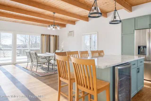 a dining hall with stainless steel appliances granite countertop a dining table chairs and a chandelier
