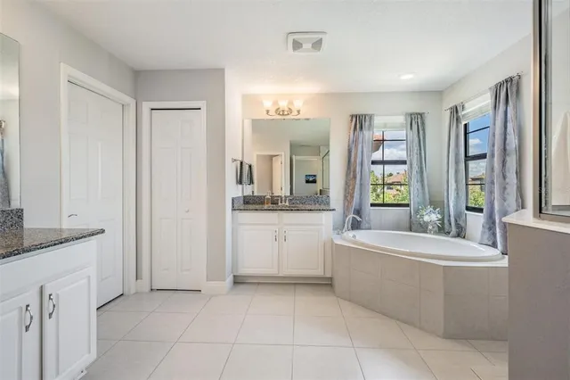 a spacious bathroom with a double vanity sink a mirror and a bathtub