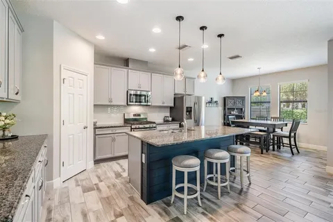 a kitchen with stainless steel appliances granite countertop a table chairs sink refrigerator and microwave