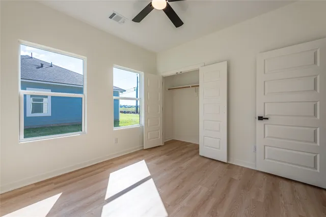 a view of an empty room with a window and wooden floor