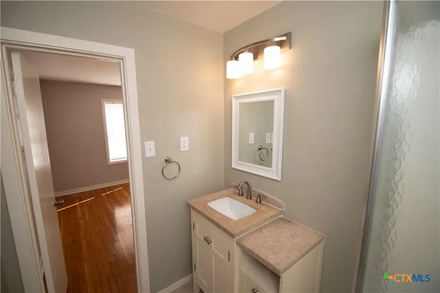 a bathroom with a sink a light fixture a mirror and a toilet