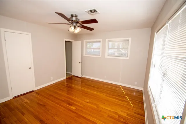 a view of an empty room with wooden floor and a window