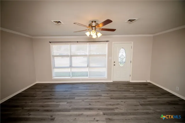 a view of an empty room with window and wooden floor