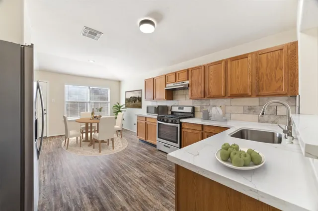 a kitchen with stainless steel appliances granite countertop a sink a stove and a wooden floors