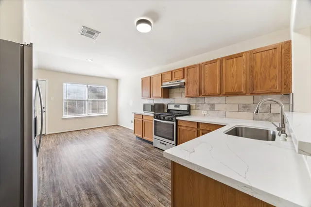 a kitchen with granite countertop a sink wooden cabinets and stainless steel appliances