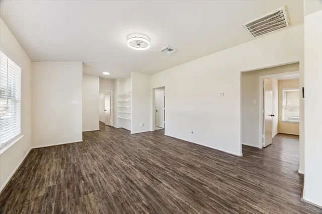 a view of empty room with wooden floor and windows