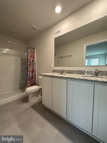 a bathroom with a granite countertop sink mirror and toilet