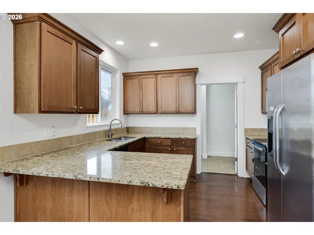 a kitchen with granite countertop a sink a refrigerator and wooden cabinets