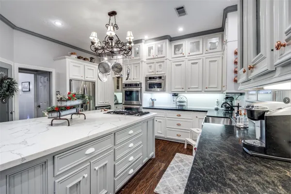 a kitchen with stainless steel appliances granite countertop a sink dishwasher stove and white cabinets with wooden floor