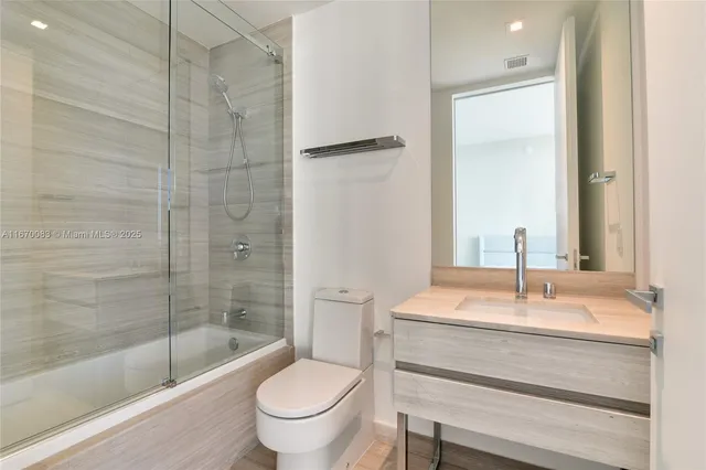 a bedroom with two beds and next to a window