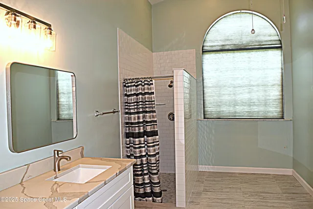 a bathroom with a granite countertop sink a mirror and shower