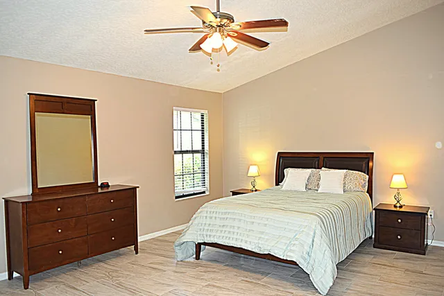 a bedroom with a bed and a dresser with wooden floor
