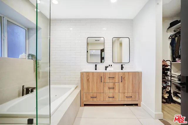a bathroom with a double vanity sink mirror and bathtub