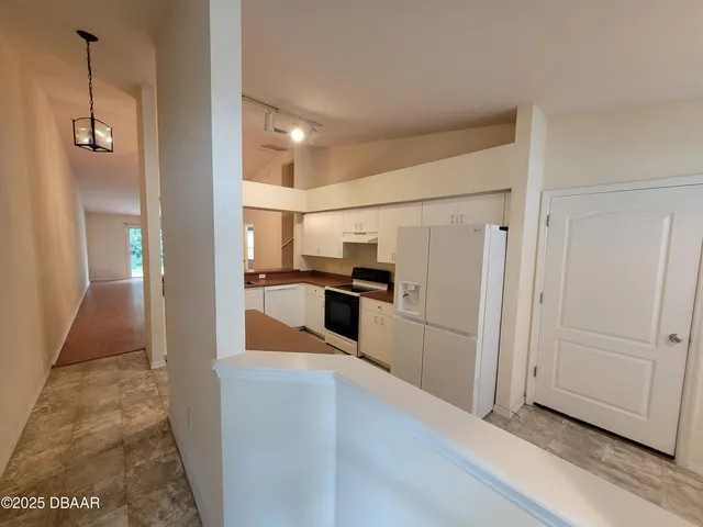 a kitchen with stainless steel appliances granite countertop a refrigerator a sink dishwasher a stove and white cabinets with wooden floor