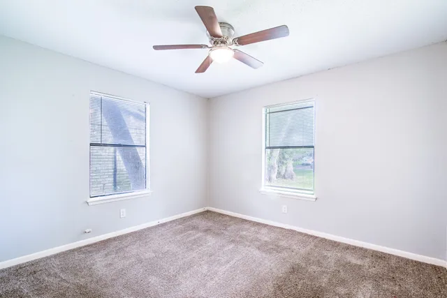 an empty room with windows and fan