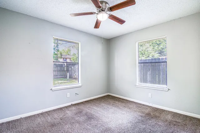 an empty room with a window and a ceiling fan
