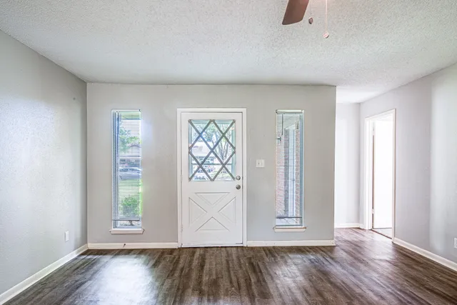an empty room with wooden floor and windows