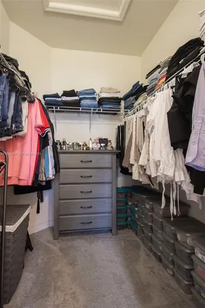 a view of walk in closet with clothes and shoes