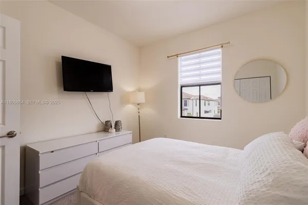 a bedroom with a bed a flat screen tv and a window