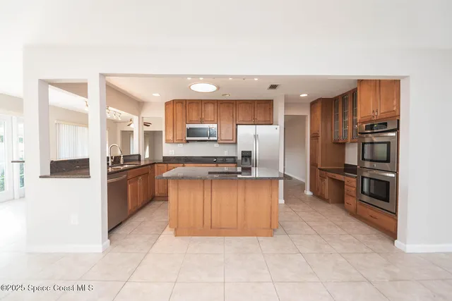 a large kitchen with stainless steel appliances a refrigerator a stove a microwave and cabinets
