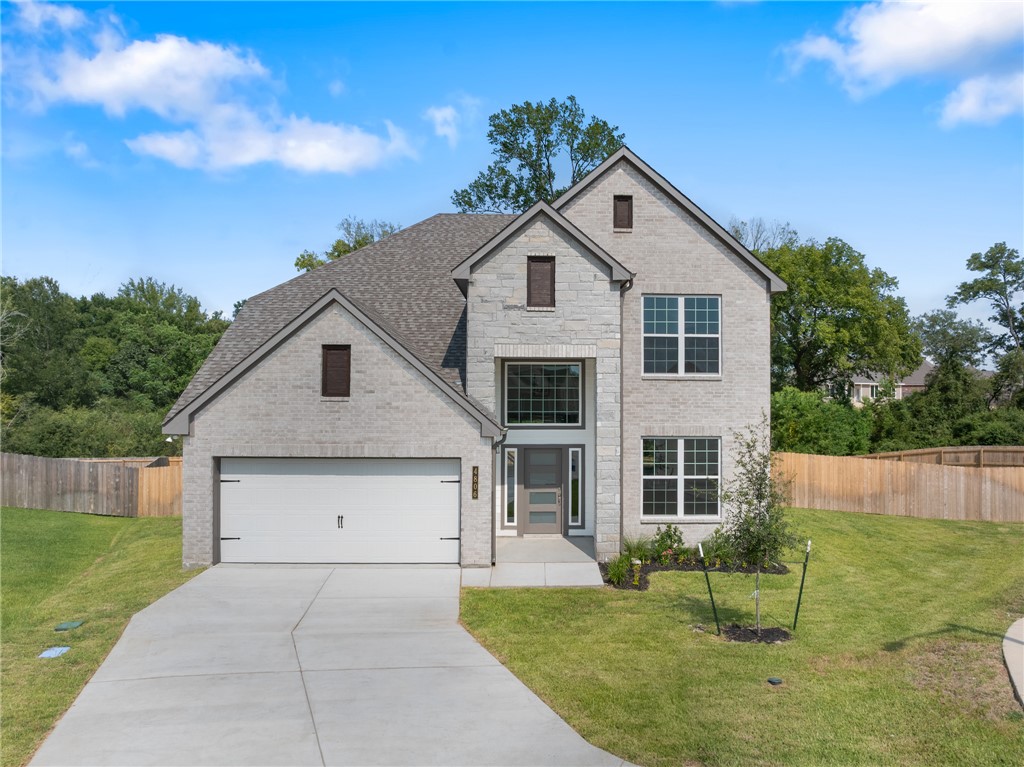 View of front of home featuring brick siding, an attached garage, driveway, and roof with shingles