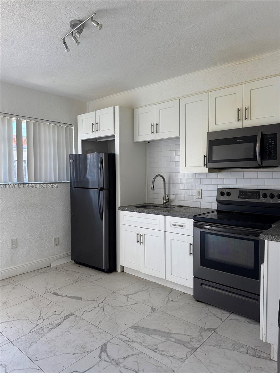 903 80th Street Miami Beach, FL 33141 - Photo 10 of 15 a kitchen with a refrigerator sink and white cabinets
