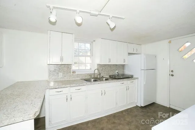 a kitchen with stainless steel appliances granite countertop a sink a stove and refrigerator