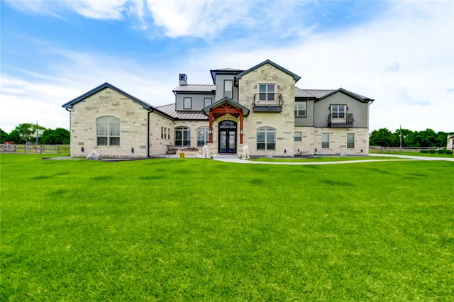 a front view of a house with a yard and large trees