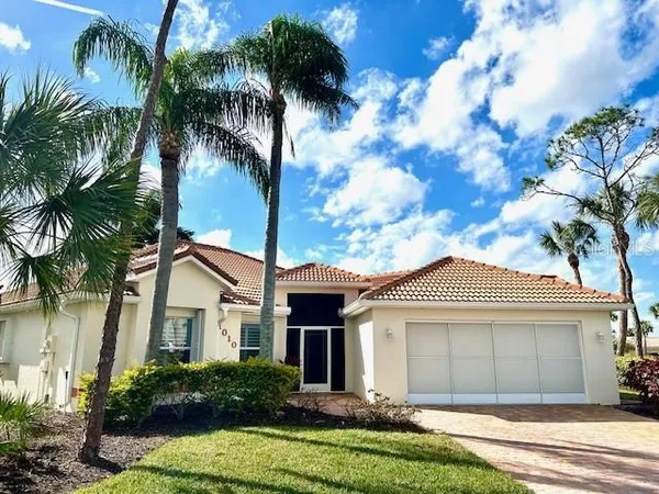 a view of a white house next to a yard with palm trees