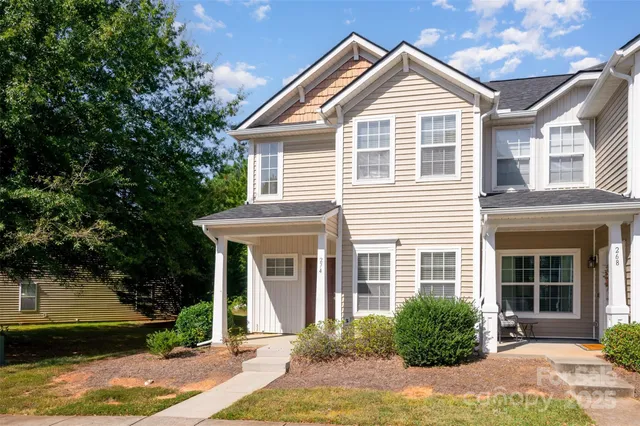 a view of a house with a yard plants and large tree