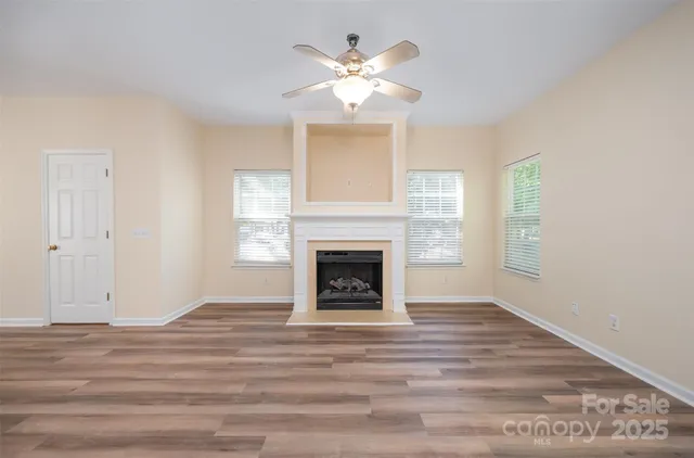 a view of an empty room with chandelier fan and fire place