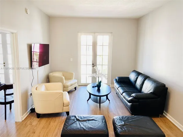 a living room with furniture a flat screen tv and a window