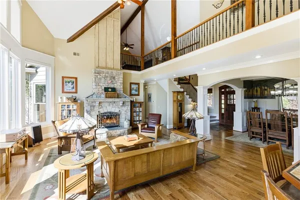 a kitchen with stainless steel appliances kitchen island granite countertop a refrigerator a stove a dining table and chairs with wooden floor