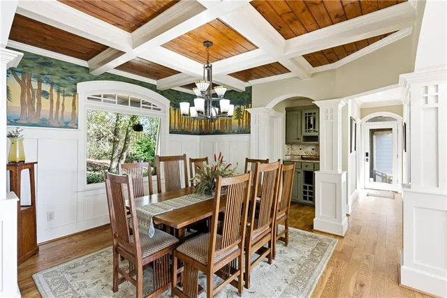 a kitchen with stainless steel appliances kitchen island granite countertop a refrigerator a stove a dining table and chairs with wooden floor