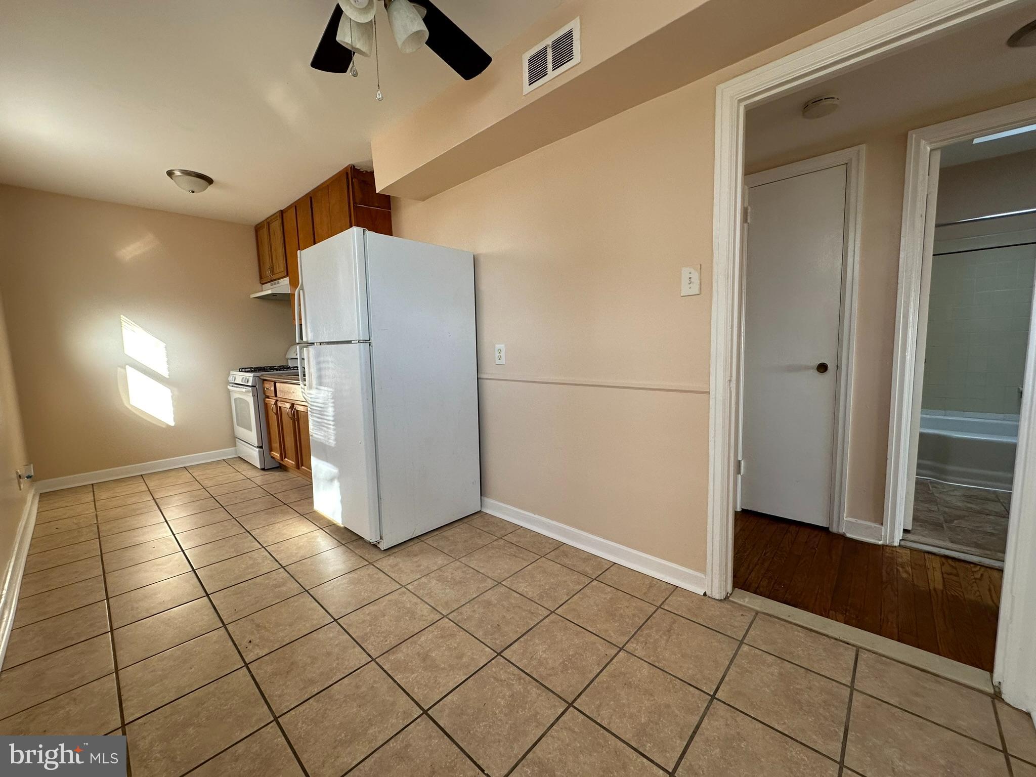 517 East Tabor Road, Unit 2 Philadelphia, PA 19120 - Photo 10 of 23 a view of a refrigerator in kitchen and an empty room with wooden floor