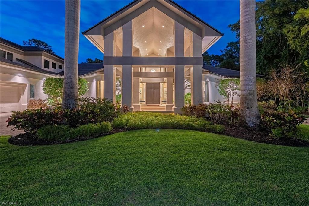 2701 Buckthorn Way Naples, FL 34105 - Photo 1 of 48 a view of a brick house with a large windows and a yard with plants and large trees